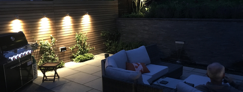 A contemporary granite patio and retaining wall with lighting