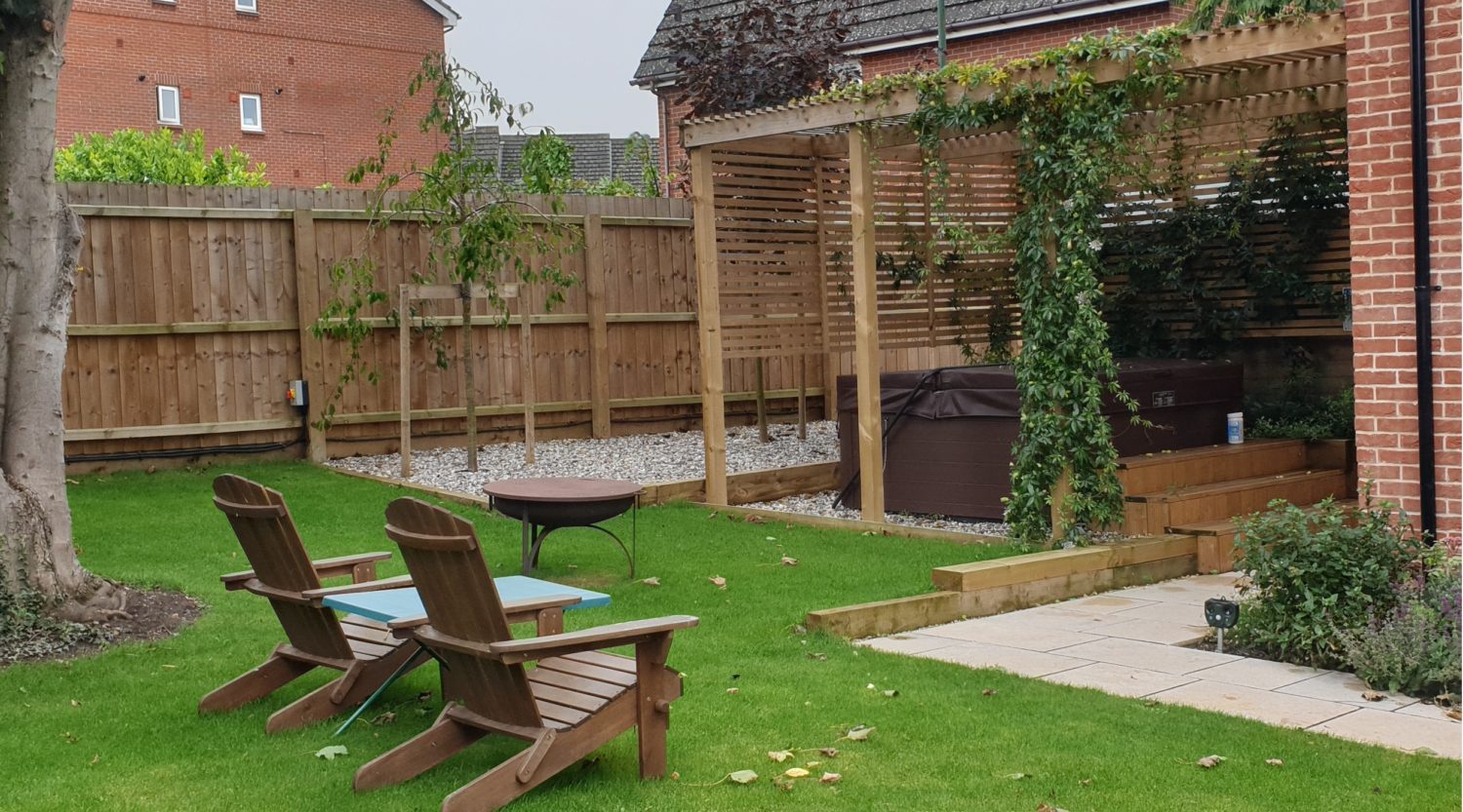 A hot tub under a bespoke wooden pergola with firepit